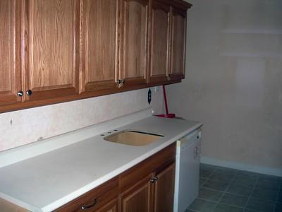 An old kitchen with used wooden kitchen cabinets and a white countertop, a retro design.