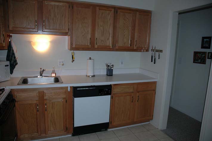 A white painted kitchen with wooden cabinet doors, white marble countertop space looking well-organized