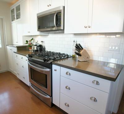 A black and white shaded kitchen with used black countertops and white cabinets mounted to the wall.