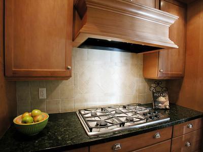 A kitchen interior with a wooden kitchen exhaust in the middle and cabinets on the sides.