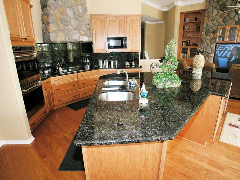 a black and dark kitchen countertop option with brown cabinets and flooring