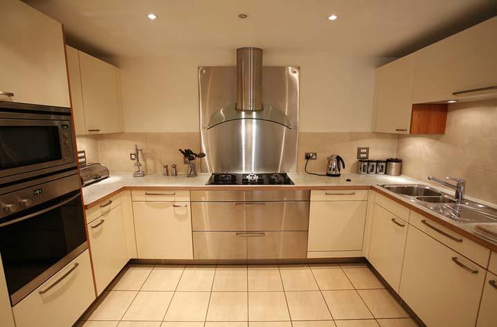 Off-white finish cabinet kitchen doors and shelf with a stainless steel hood in the center and a stainless steel sink at right side