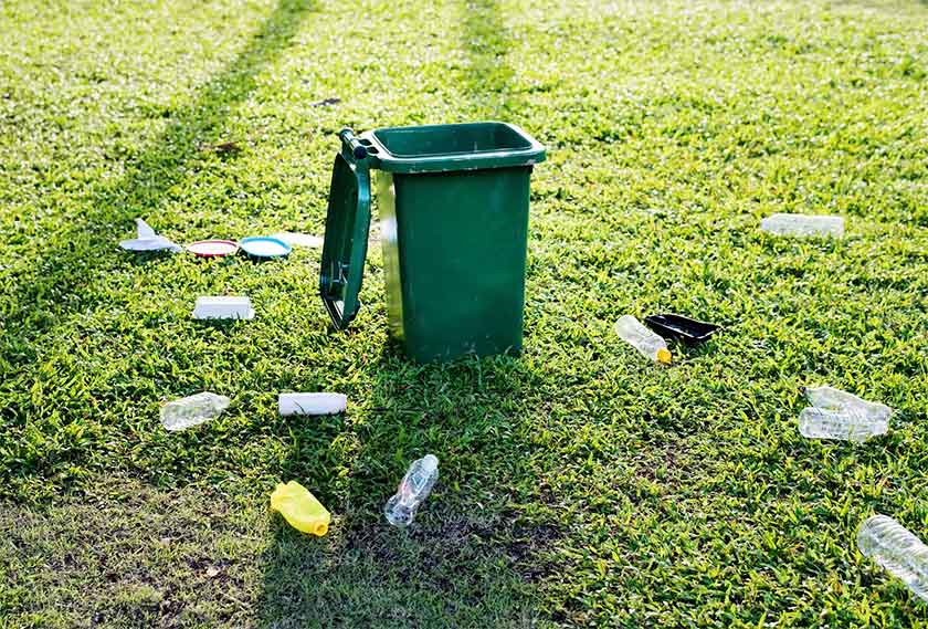 fresh dust bin in a park with trash lying around