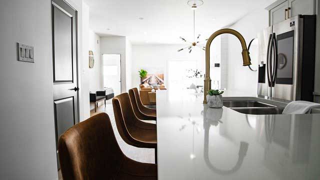 appliances aligned with along the countertop and sink of a white shiny kitchen