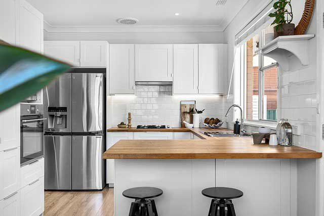 white cabinets and silver fridge with brown counterops.