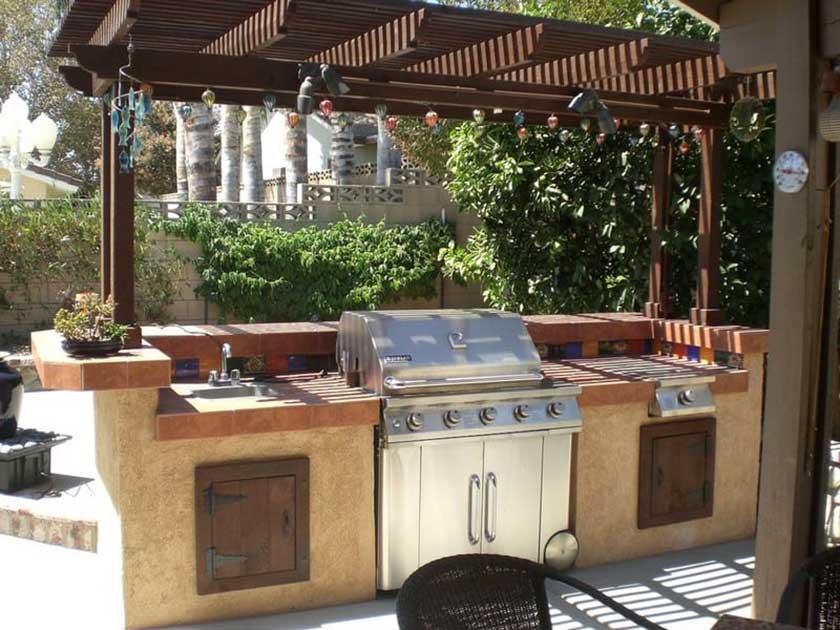 grill in between the countertops of an outdoor kitchen within the backyard of house