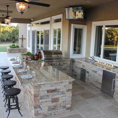 a kitchen with marble in slate color and walls of brick and grill